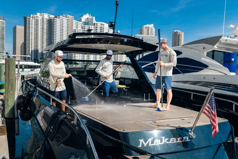 Three YMS crew members washing down the deck of a yacht in Miami