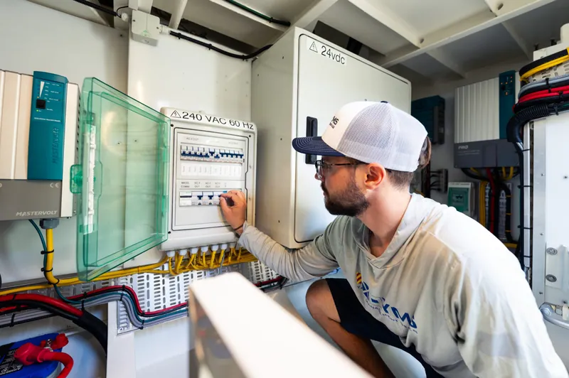 A YMS technician working in an electrical panel aboard a vessel