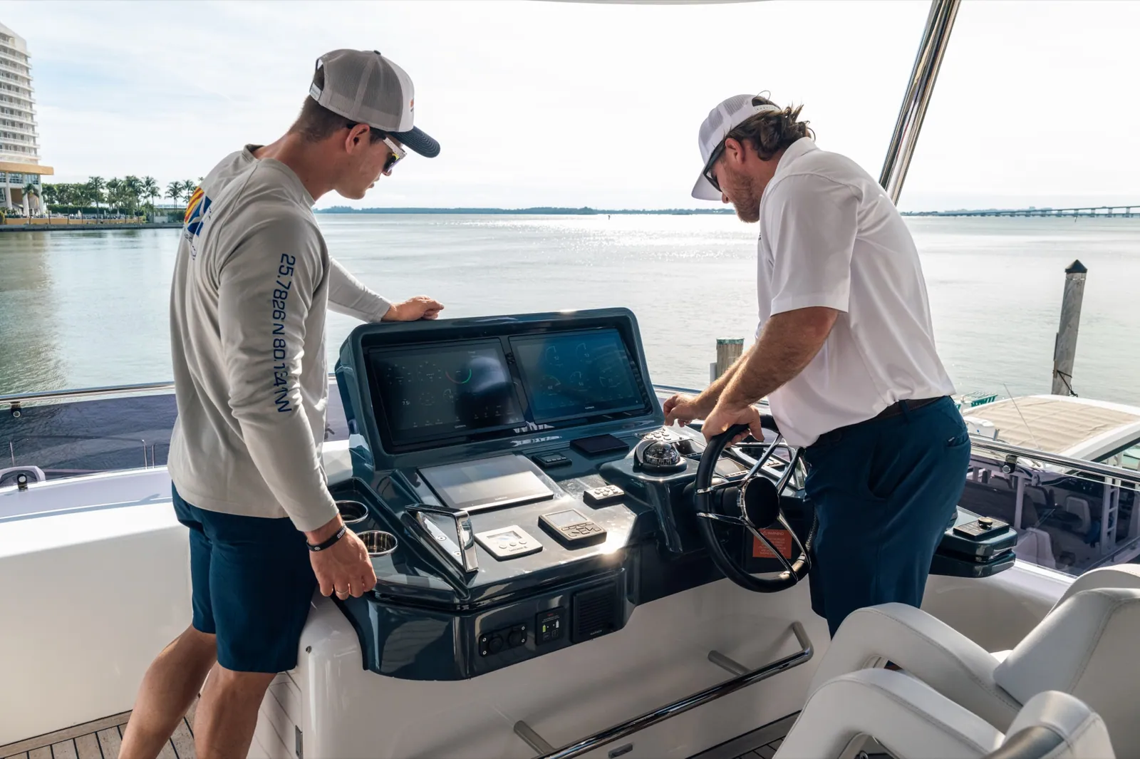 Two YMS crew at the helm console of a yacht, open water past the windshield