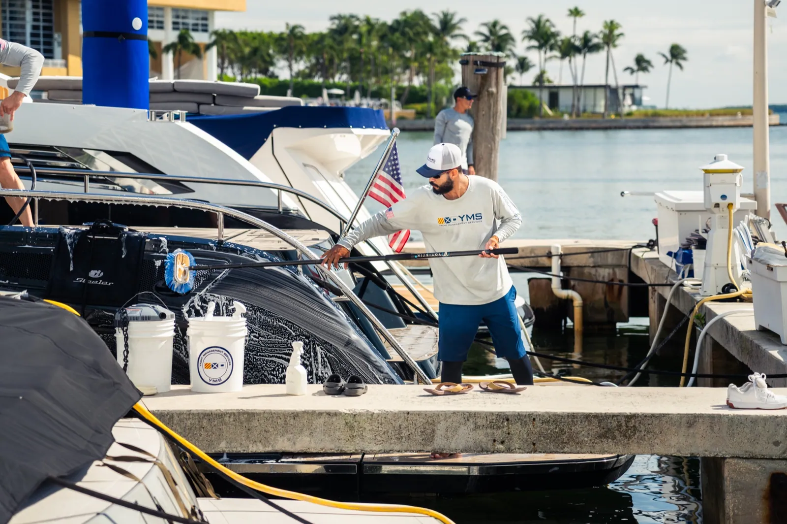 A YMS crew member at the dock beside a yacht with the cleaning kit laid out